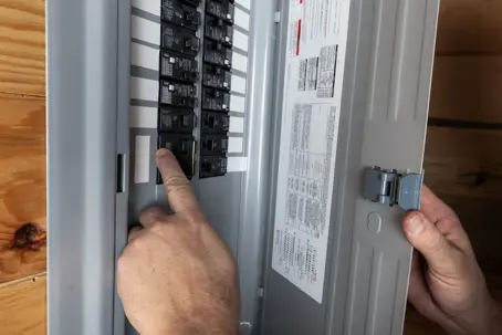 person pointing at circuit breaker in panel