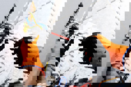 A person wearing orange and black gloves installs an electrical switch