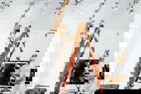 Two men are installing track lighting