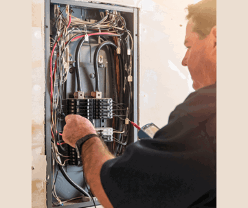 electrician tests an open electrical panel